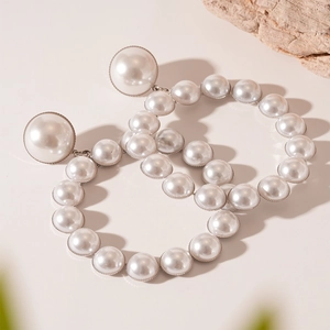 Détail macro de boucles d'oreilles créoles avec perles nacrées sur un fond de pierre naturelle