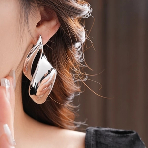 Close-up of oversized silver irregular leaf earring showing metallic luster on model