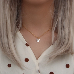 Elegant gold stainless steel necklace featuring a white shell butterfly pendant on a model