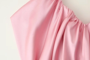 Dettaglio dell'abito in raso rosa con trama plissettata e lucentezza simile alla seta