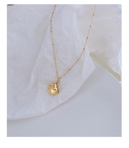 Detail view of a 18k gold plated stainless steel necklace with fish tail round pendant