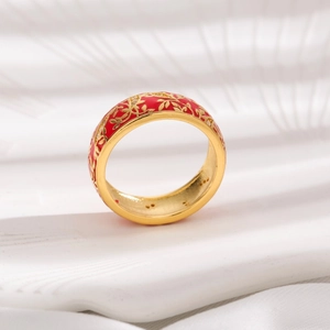 Detail of vintage gold-plated ring featuring red enamel finish and intricate flower engraving