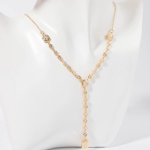 Detail of a gold Y-shaped necklace with zircon pendants on a white jewelry bust