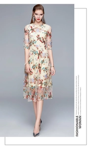 Detail of elegant beige dress with multi-color floral embroidery and sheer mesh sleeves
