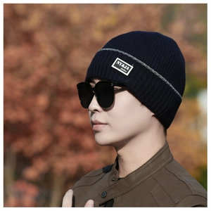 Detail view of navy blue knitted beanie with gray accent line and fashion textile label