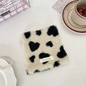 Macro shot of fluffy square plush coaster with cow print heart pattern and gold label