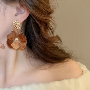 Close-up of model wearing acrylic flower earrings with golden metal texture detail