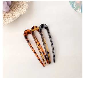 Detail of three resin U-shaped hairpins with tortoiseshell leopard patterns on lace