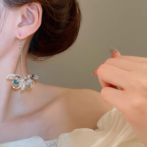 Close-up of model wearing acrylic bow earrings with blue and green internal accents