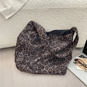 Detailed view of leopard print suede tote bag placed on a cozy white fleece sofa