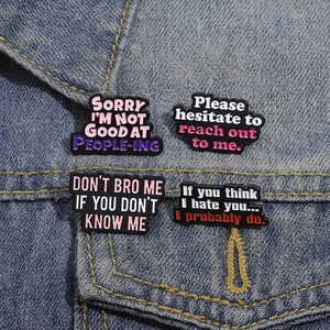 Set of four enamel slogan pins displayed on a blue denim jacket pocket with sharp detail