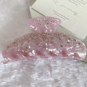 Vue détaillée de la pince à cheveux en résine rose avec strass et texture nacrée
