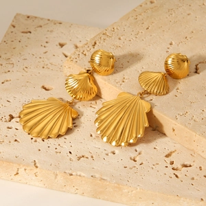 18K gold stainless steel triple shell drop earrings on a textured stone background