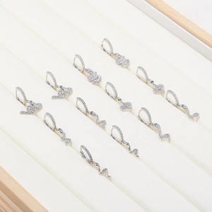 Gros plan de boucles d'oreilles serpent argentées avec zircons et yeux verts sur velours
