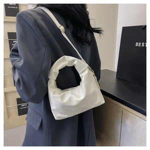 Detail of white pleated crescent bag in soft leather with adjustable shoulder strap and gold clasp