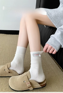 Detail of white ribbed cotton socks featuring red text fabric label and chic side tag