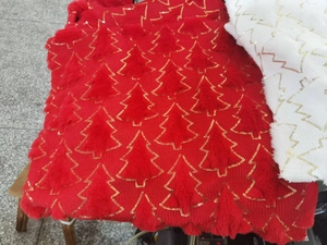 Detailed close-up of red plush fabric with golden sequin Christmas tree patterns