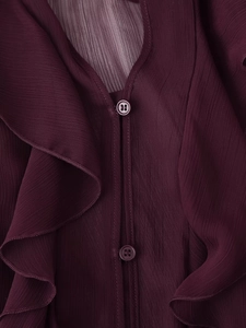Dettaglio camicia bordeaux con volant che mostra trama del tessuto e bottoni