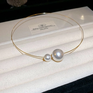 Close-up of golden irregular pearl choker on cream velvet tray with soft lighting