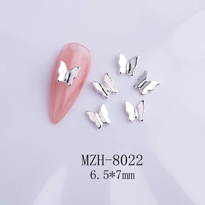 Macro shot of silver bow nail art charm sized 6.5x7mm on a pink mannequin nail