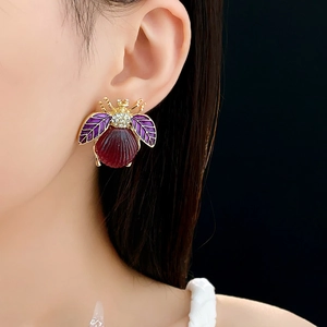 Detailed view of a vintage beetle stud earring with red shell and purple crystal accents