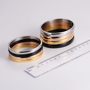 Minimalist stainless steel cuff bracelets in four colors shown with measuring ruler