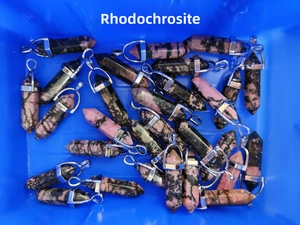 Bulk display of natural rhodonite hexagonal point pendants in a warehouse setting