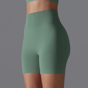 Detail showing seamless high-waist ribbed waistband and peach lift on green yoga shorts