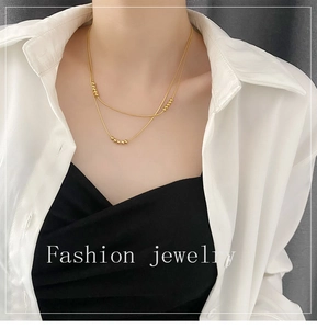 Close-up of double-layer gold chain necklace with small beads on a model