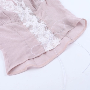 Detailed close-up of pink lace-up tank top with white lace edges and metal eyelets