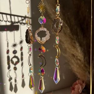 Golden sun catcher with natural agate and crystal prisms reflecting rainbow light on wall