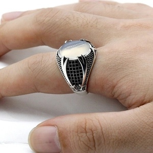 Macro shot of men's vintage silver ring with white oval gemstone and ornate carvings