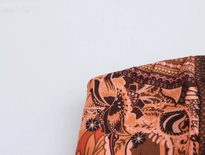 Vue détaillée du motif cachemire bohème sur tissu de robe tissé orange et marron