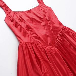 Detail of red satin dress featuring corset bone lines and elegant gathered hem pleats