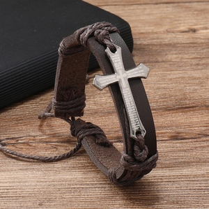 Close-up of vintage dark brown woven leather bracelet with silver cross and Spanish prayer