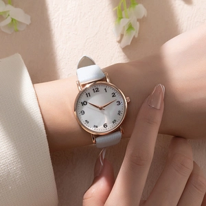 Close-up of minimalist women's quartz watch with white leather strap and rose gold case