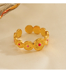 Detail shot of 18K gold plated ring with pink enamel sunburst patterns on fabric