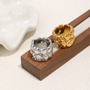 Detail of lava texture rings in gold and silver finish with inlaid zircons on wood