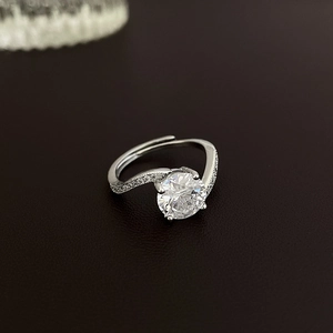 Macro detail of adjustable open ring featuring round zircon center stone and twisted band