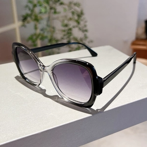 Detail of oversized sunglasses with purple gradient lenses and two-tone transparent frames
