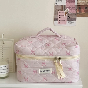 Detail of pink quilted cosmetic bag with bow embroidery and ribbon zipper pull