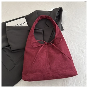 Close-up of burgundy suede tote bag featuring a decorative bow and soft velvet texture
