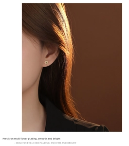 Close-up of a model wearing a rose flower stud earring with polished gold finish