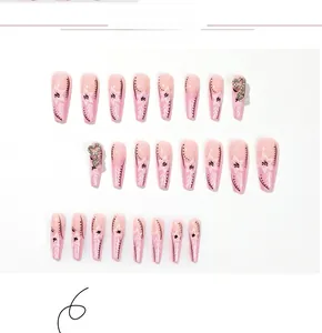 Détail des faux ongles French roses avec motifs floraux blancs et strass en forme de cœur