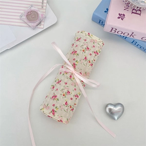 Detailed macro view of a floral fabric makeup brush roll wrap with a soft pink ribbon tie