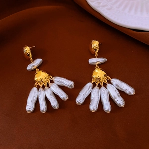 Detail of flower earrings with gold textured metal and baroque pearl tassel on brown velvet