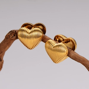 Golden heart-shaped stainless steel earrings with vertical striped texture on wood