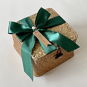 Macro view of woven gift basket with dark green ribbon, pearls, and Thank You tag
