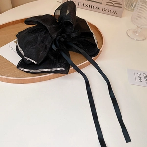 Détail de la pince à cheveux nœud noir avec bords en strass et longs rubans élégants
