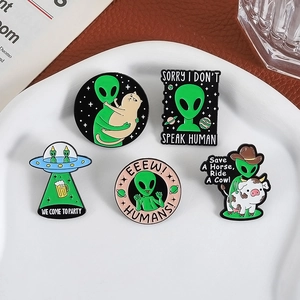 5-piece green UFO alien and cow cat enamel pin set on a white ceramic plate